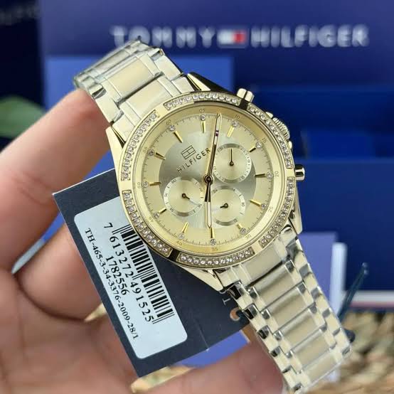 Tommy Hilfiger gold women's watch worn on wrist with product tag visible