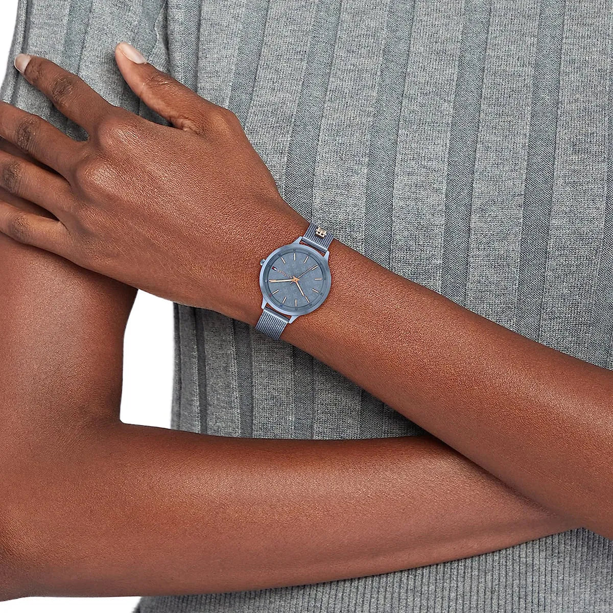 Tommy Hilfiger Iris watch worn on wrist with blue mesh strap against striped sleeve