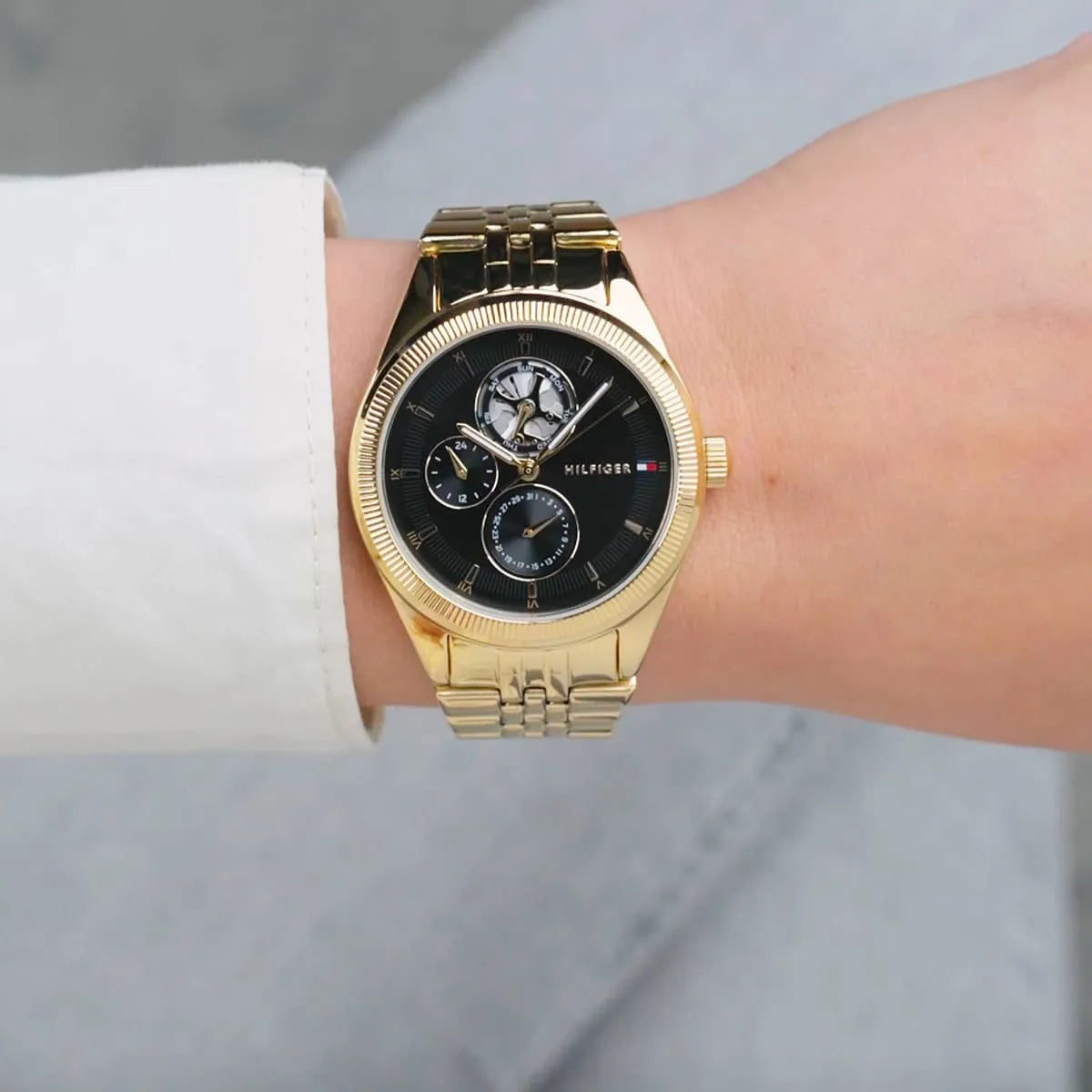 Tommy Hilfiger Monica gold watch worn on wrist with white sleeve