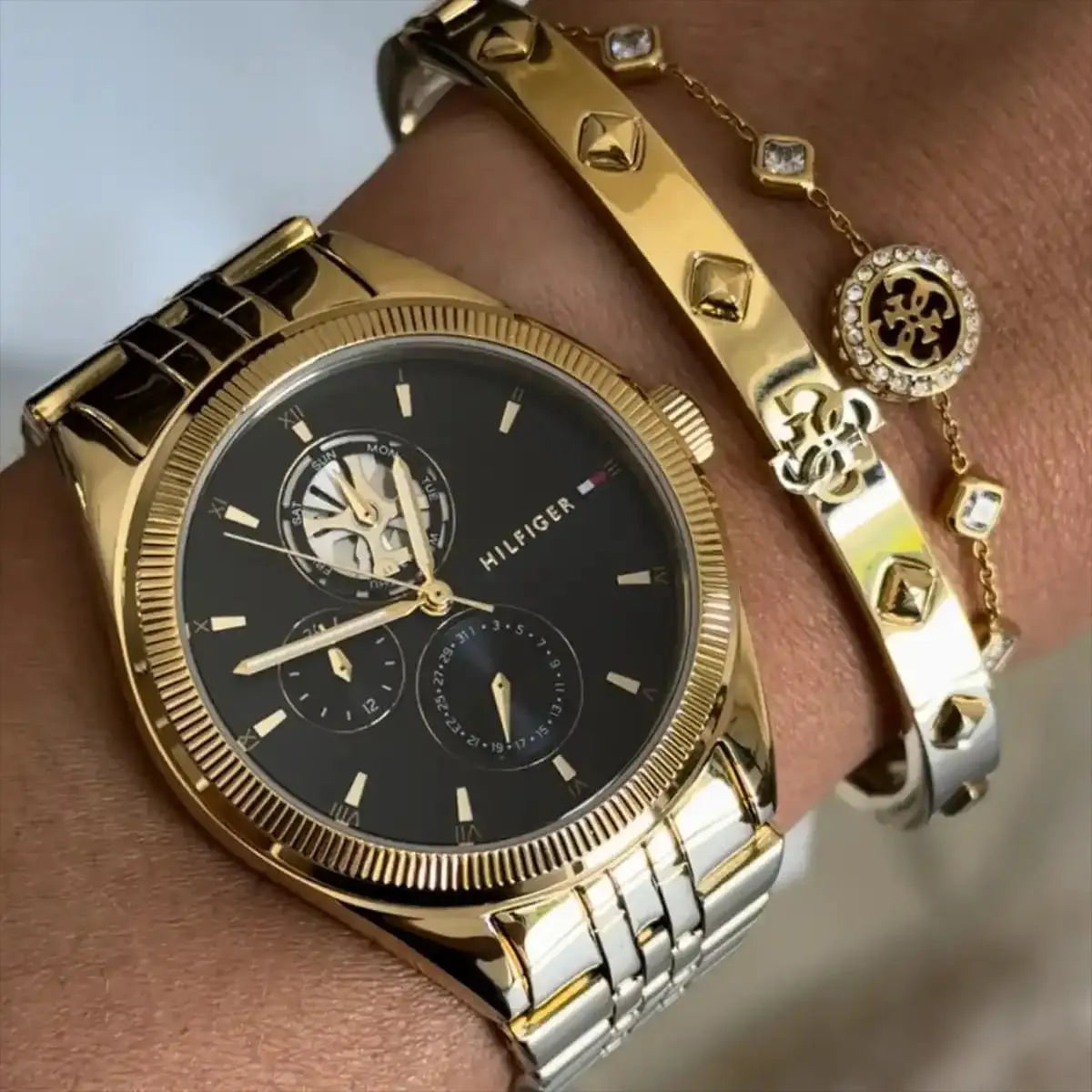 Tommy Hilfiger Monica gold watch on wrist styled with charm bracelets