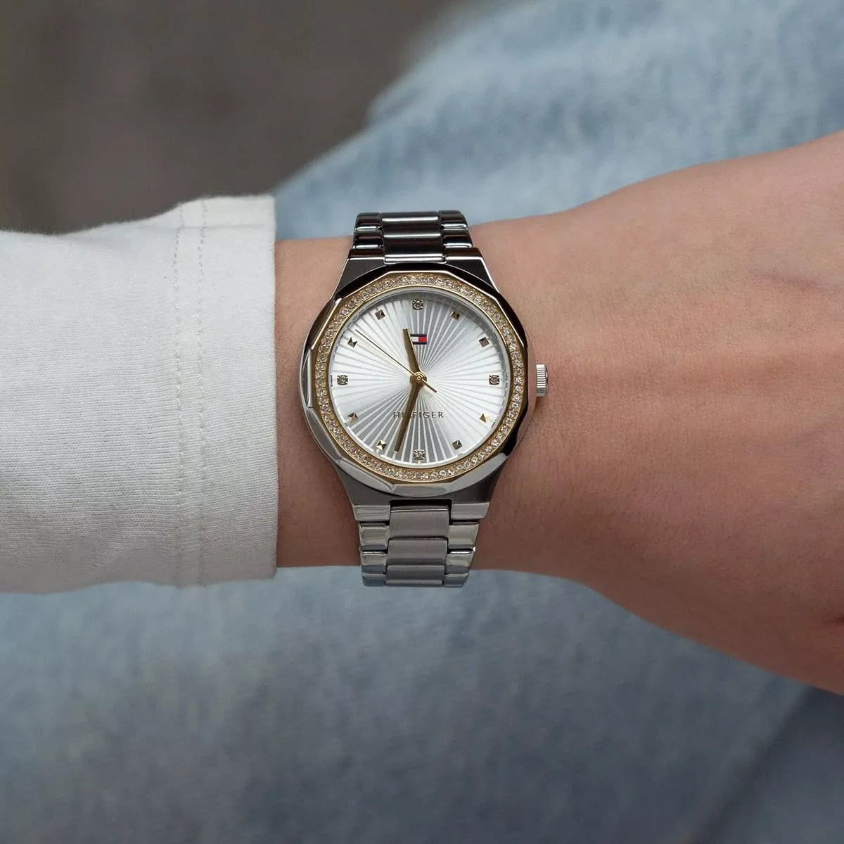 Woman wearing Tommy Hilfiger women's watch with silver sunburst dial and stainless steel bracelet