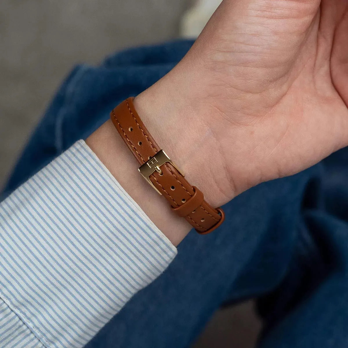 Tommy Hilfiger Mia gold-plated watch on wrist displaying brown leather strap detail