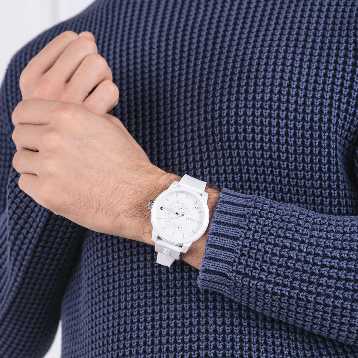 Tommy Hilfiger Denim white watch on wrist with white silicone strap, worn with blue sweater