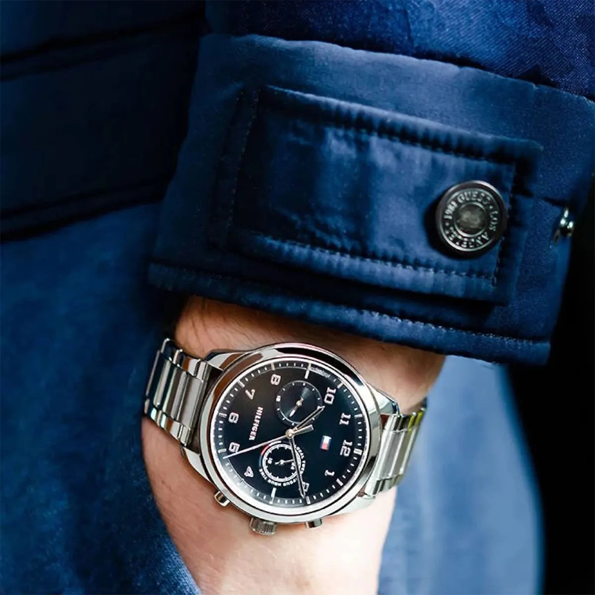Tommy Hilfiger Patrick watch worn on wrist with black dial visible against blue jacket