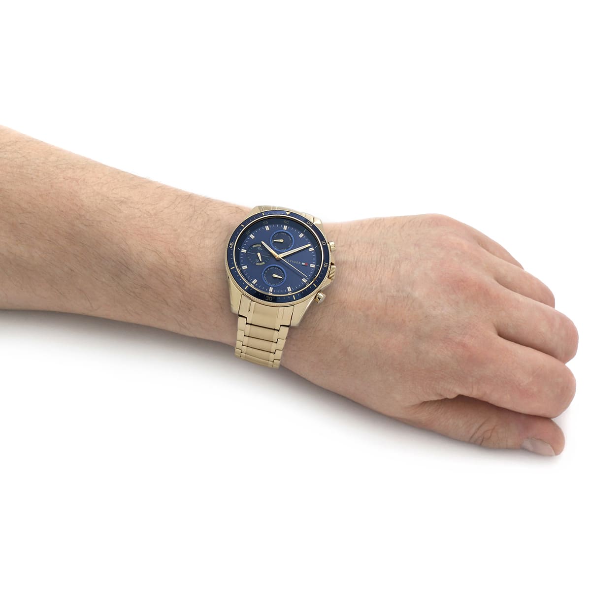 Tommy Hilfiger chronograph watch worn on male wrist with gold bracelet
