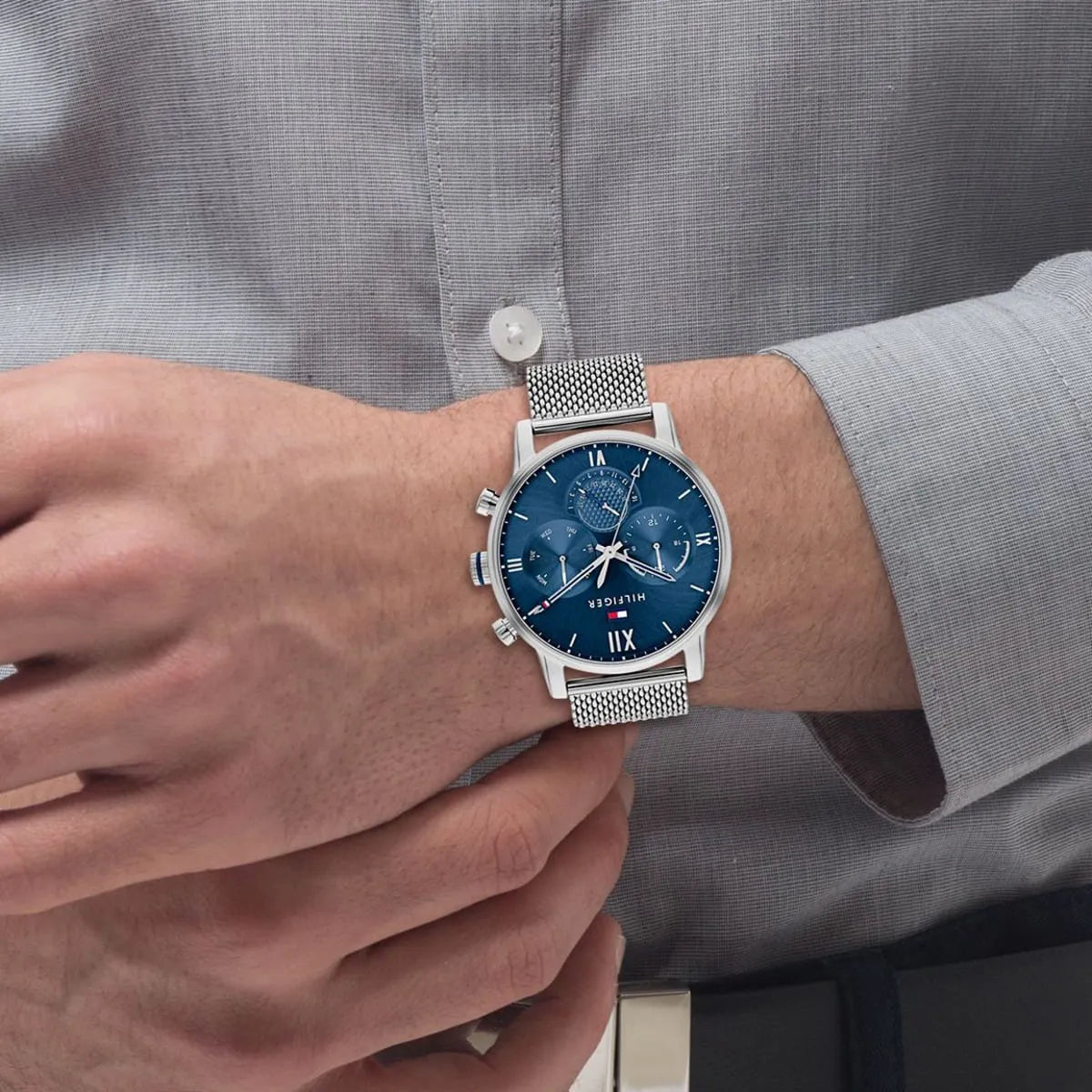 Tommy Hilfiger blue dial watch worn on wrist with silver mesh band