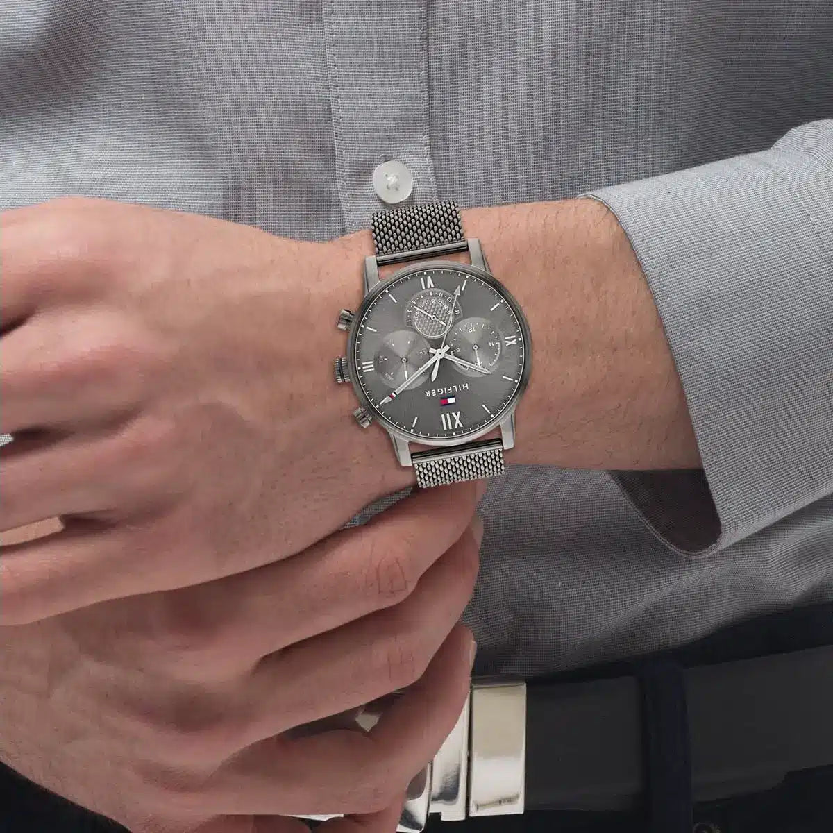 Tommy Hilfiger grey chronograph watch worn on wrist with grey mesh band