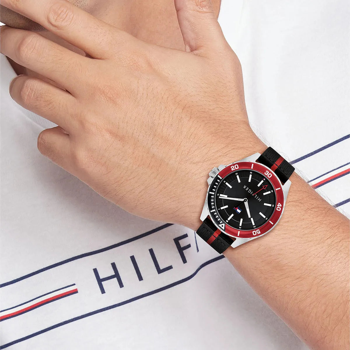 On-wrist view of Tommy Hilfiger Logan watch with black-red striped strap and red bezel