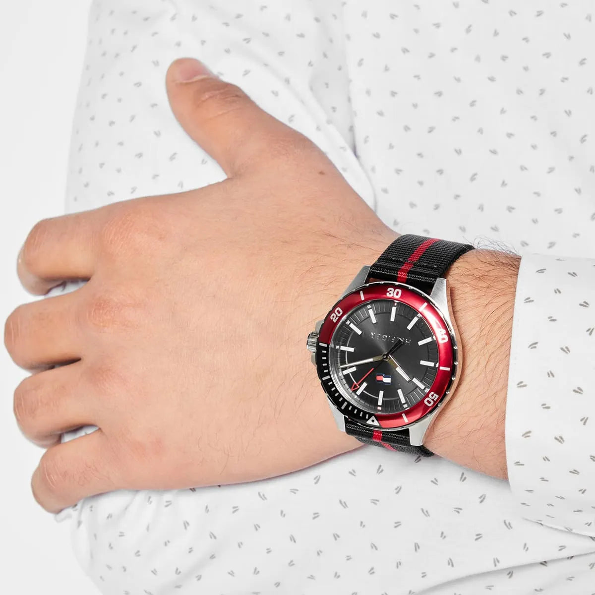 Tommy Hilfiger Logan watch worn on wrist, displaying red bezel and black dial with nylon strap