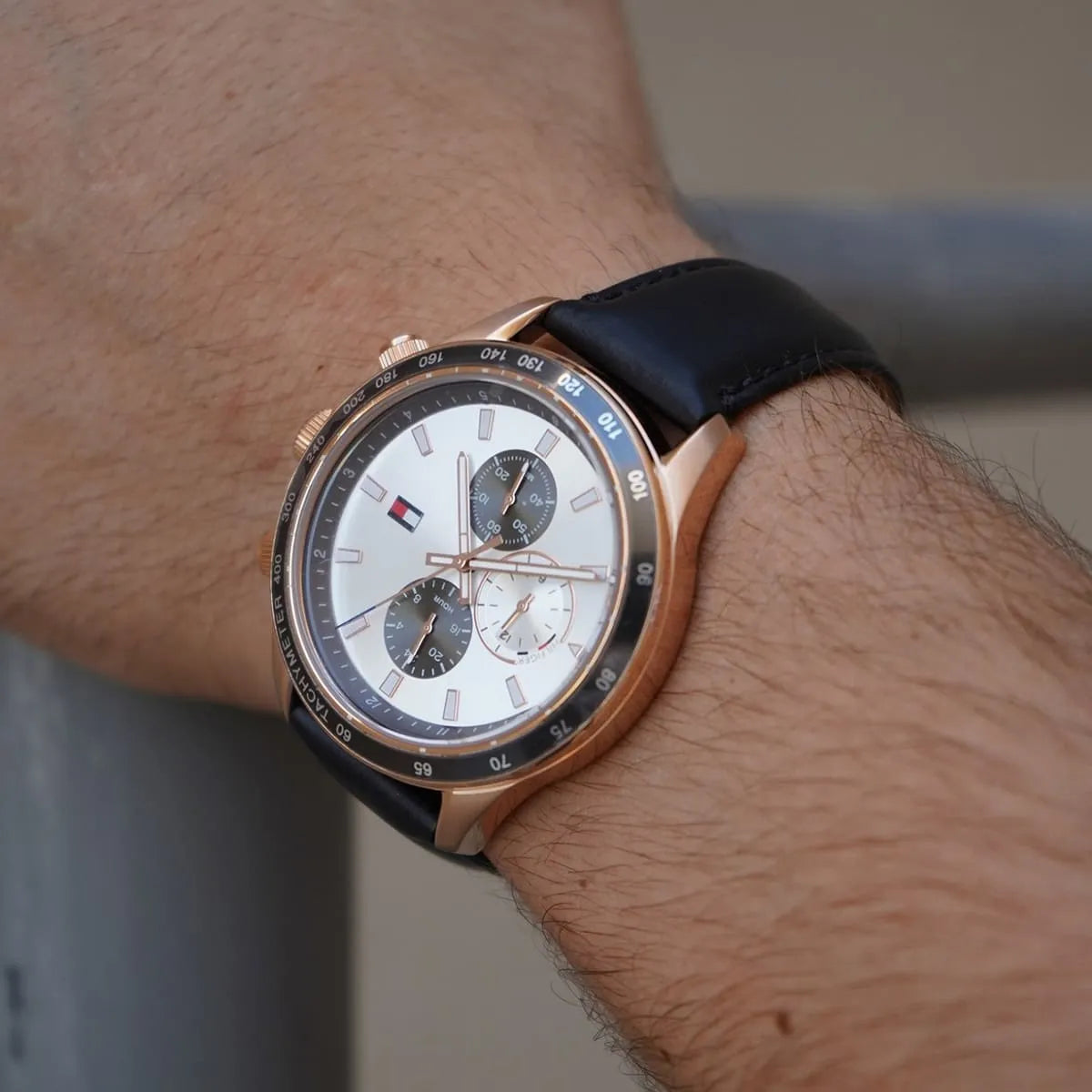 Wristwatch on wrist showing white dial with rose gold accents and subdial details