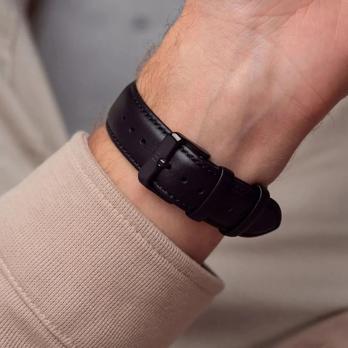 Close-up of Tommy Hilfiger TYSON black leather strap with buckle clasp and stitch detail on wrist