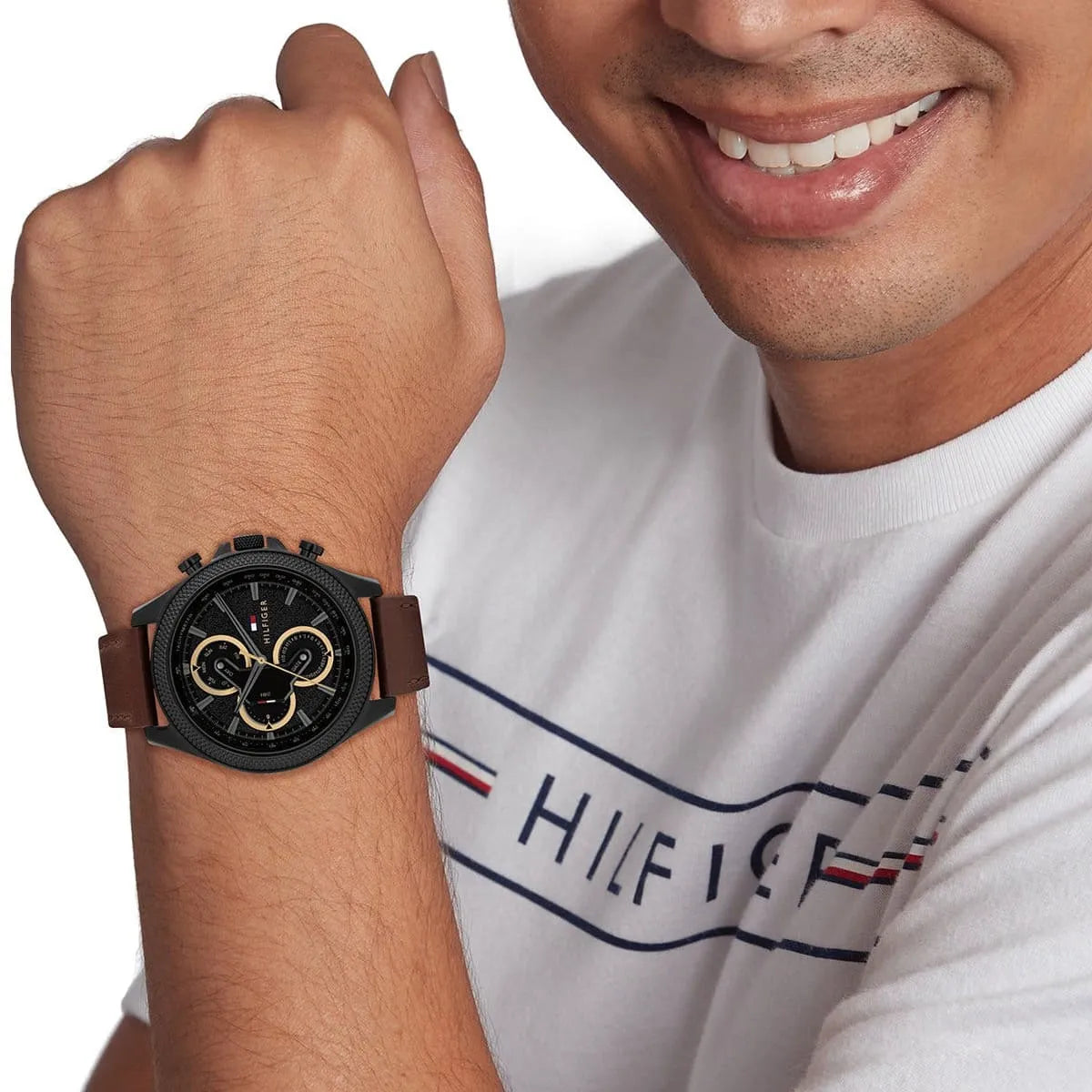 Tommy Hilfiger watch on wrist showing black dial and gold subdials in lifestyle setting