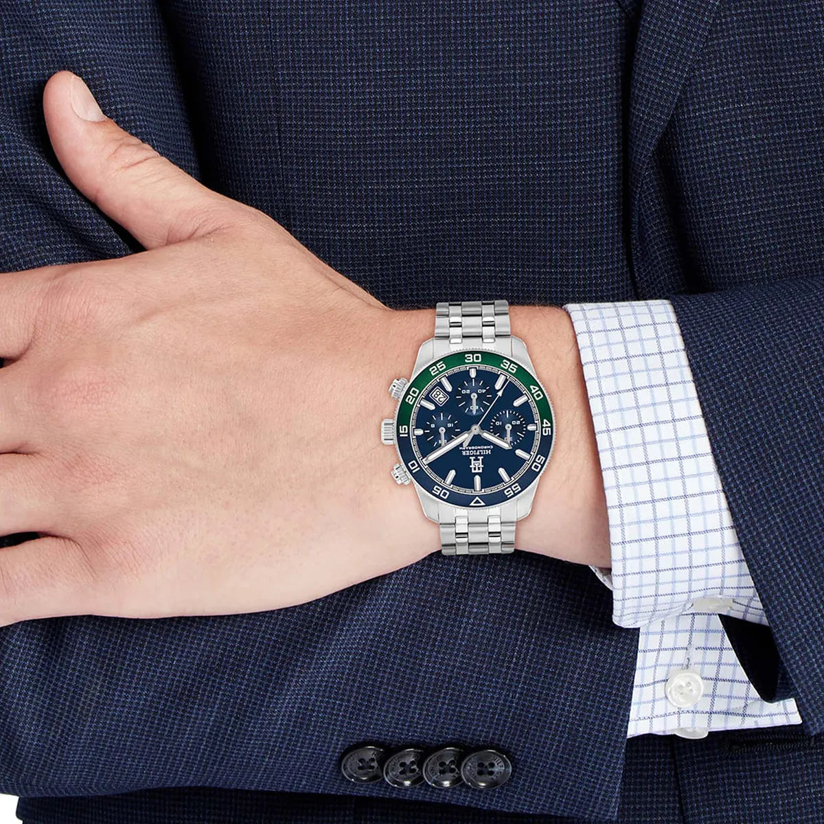 Tommy Hilfiger chronograph watch on wrist with blue dial and rotating bezel, worn with dress shirt