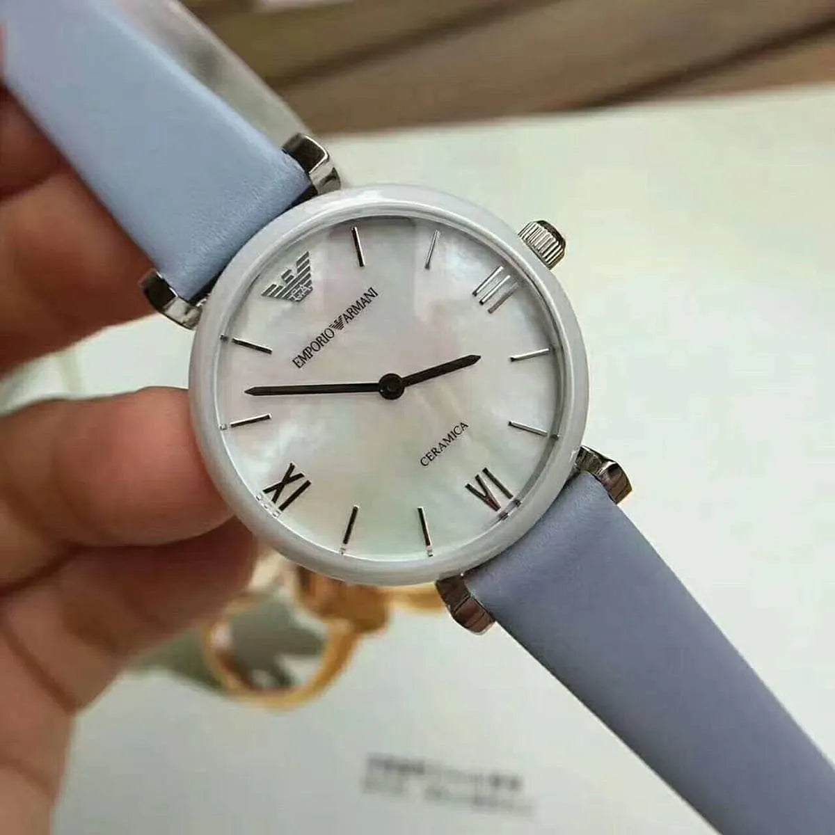 Emporio Armani Gianni T-Bar watch on wrist showing mother-of-pearl dial and grey leather strap