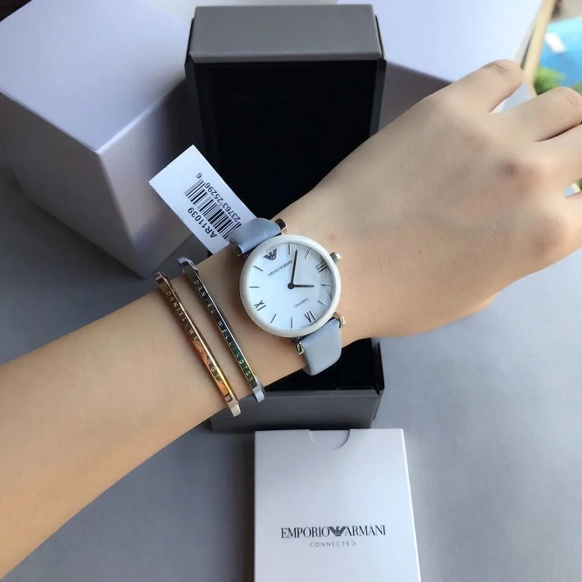Emporio Armani Gianni T-Bar women's watch on wrist with grey leather strap and mother-of-pearl dial