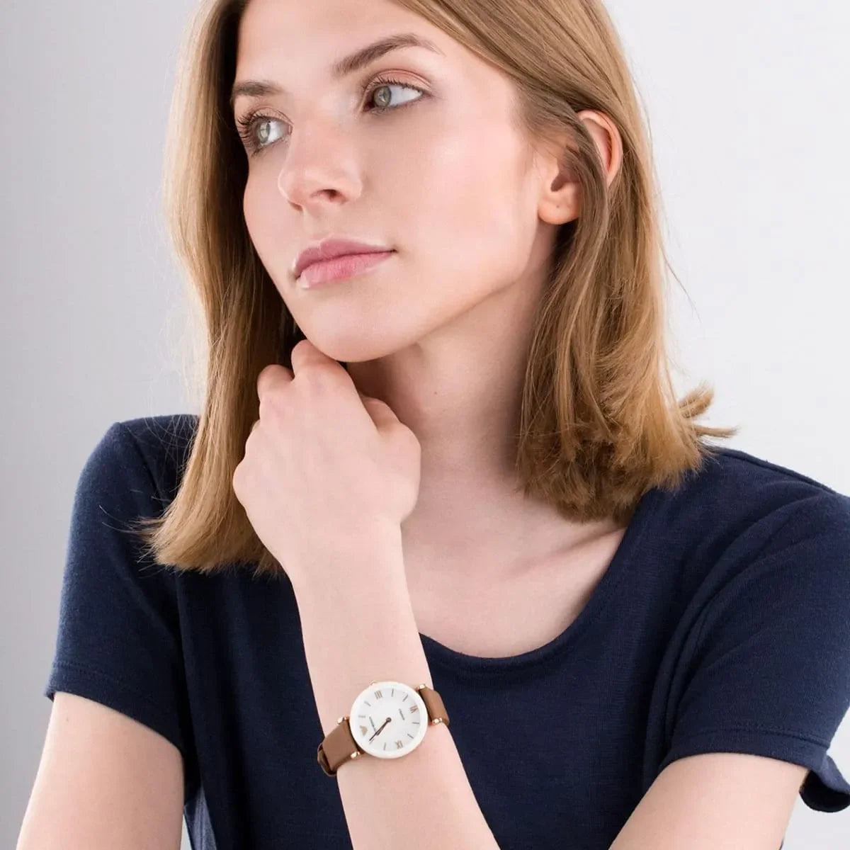 Woman wearing Emporio Armani Gianni T-Bar watch with white dial and brown leather strap