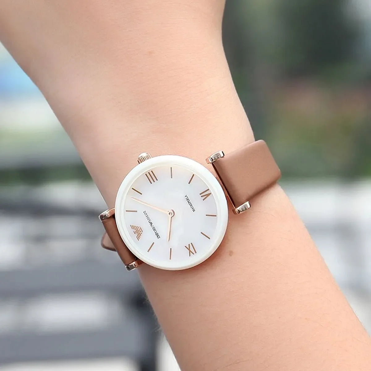 Emporio Armani Gianni T-Bar watch worn on wrist showing white dial with rose gold accents and brown leather strap