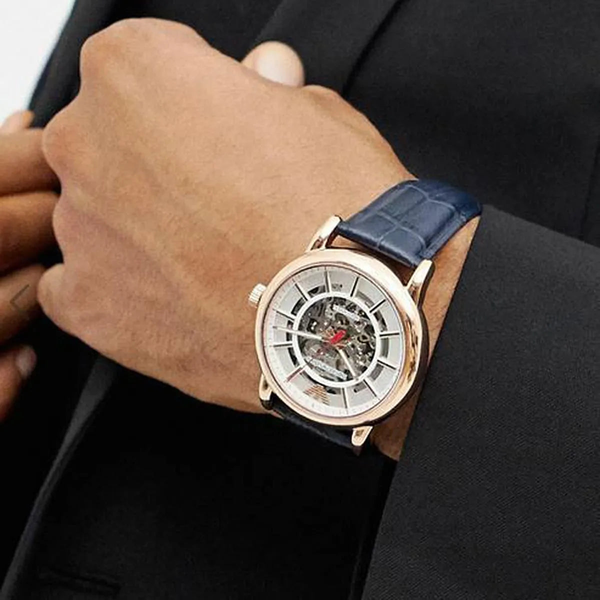 Emporio Armani AR60009 skeleton watch worn on wrist with white dial and navy leather strap