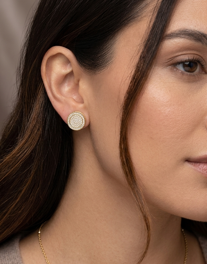 Woman wearing gold diamond pave round iced out earring on ear