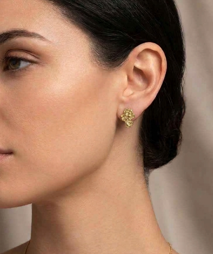 Gold asymmetrical earring worn on ear, profile view