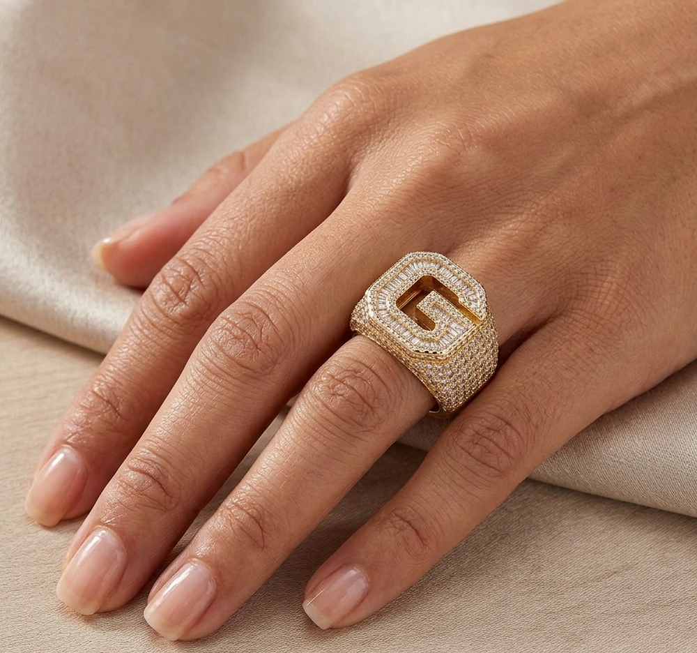 Gold baguette diamond ring worn on finger showing letter G design