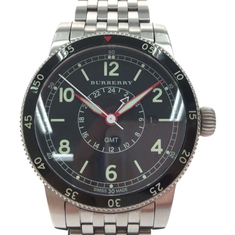 Close-up of black dial with GMT subdial, luminous hour markers, and red accents