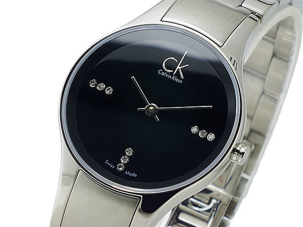 Close-up of Calvin Klein Simplicity dial showing diamond hour markers and branding on black face