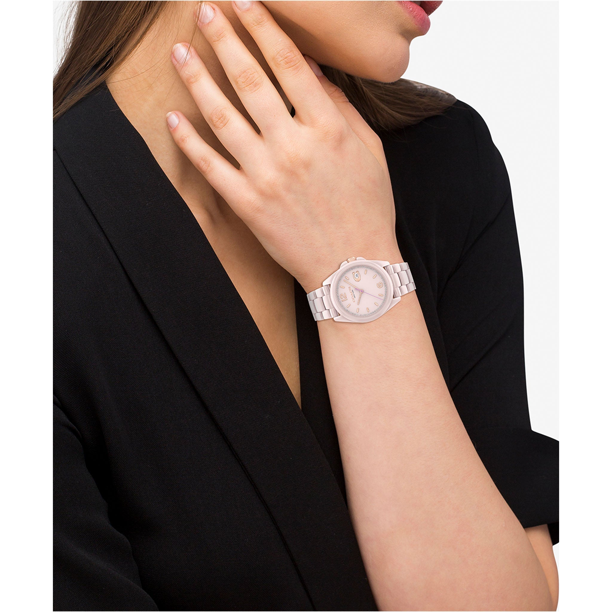 Coach Greyson pink ceramic women's watch worn on wrist with black jacket