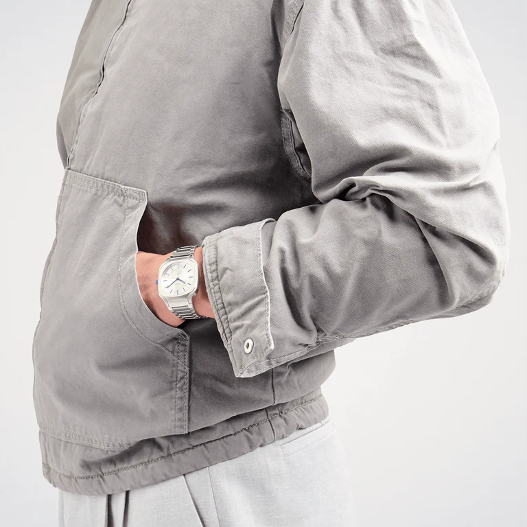 D1 Milano SQBJ01 silver square watch on wrist with gray jacket
