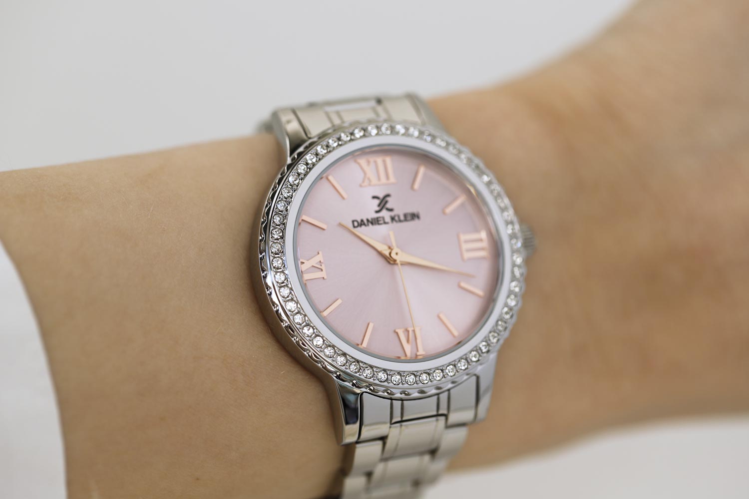 Daniel Klein pink dial watch worn on wrist, showing crystal bezel and silver bracelet