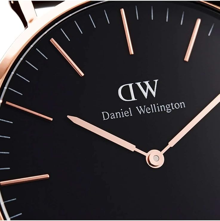 Dial detail of Daniel Wellington watch with rose gold hands and indices on black face