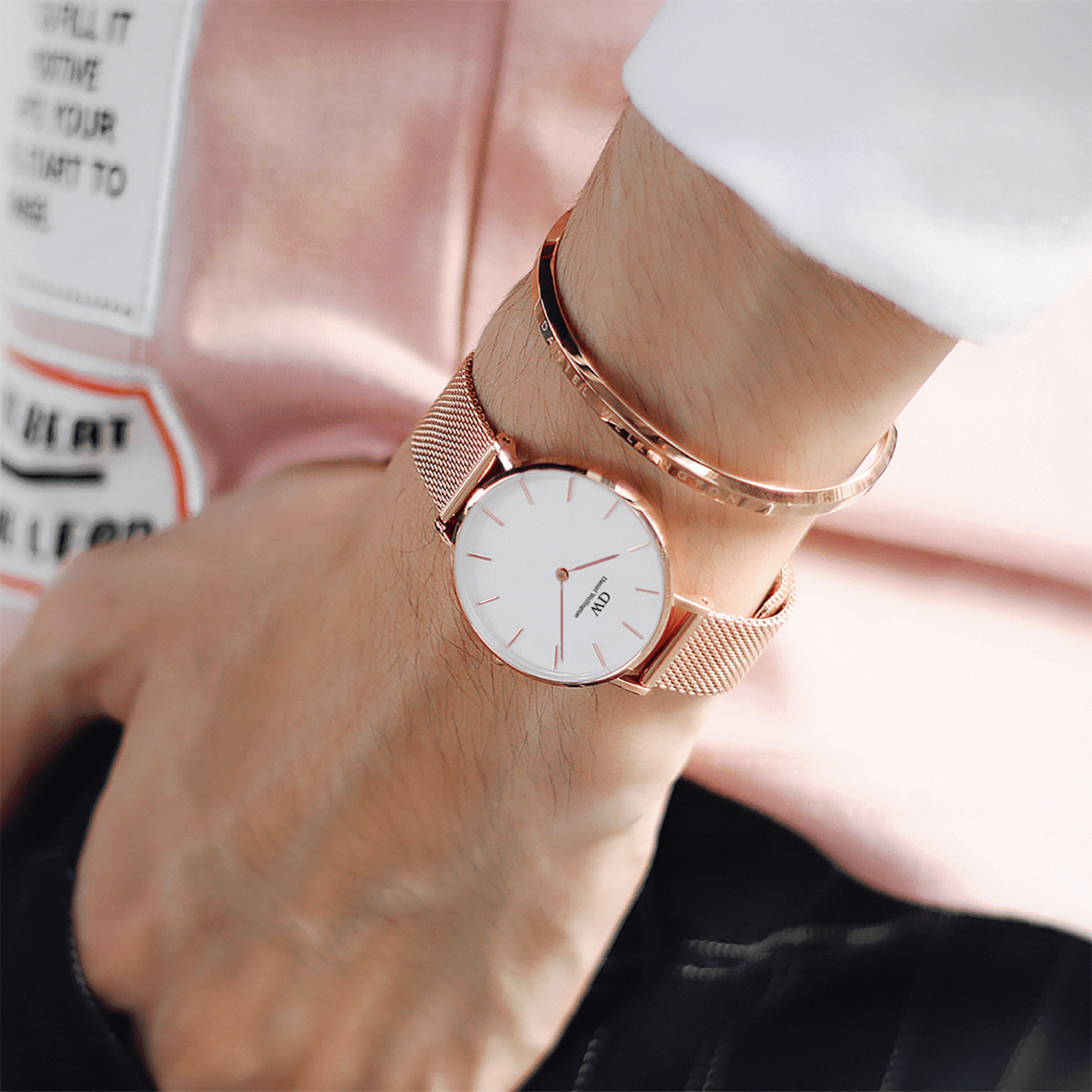 Rose gold bracelet styled with a Daniel Wellington watch on wrist, showing stackable design