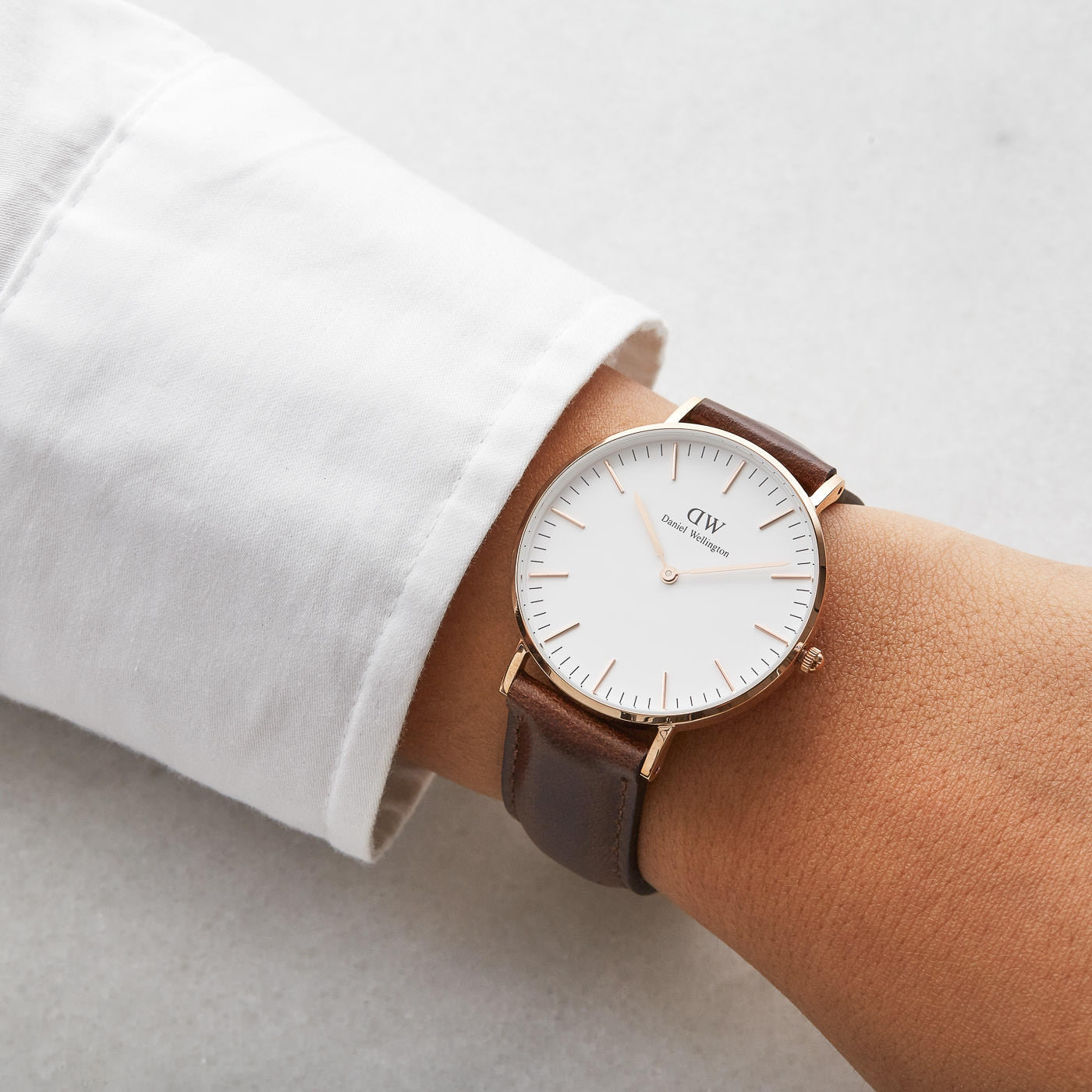 Daniel Wellington Classic Bristol 36mm worn on wrist with white dial and gold case visible against white sleeve