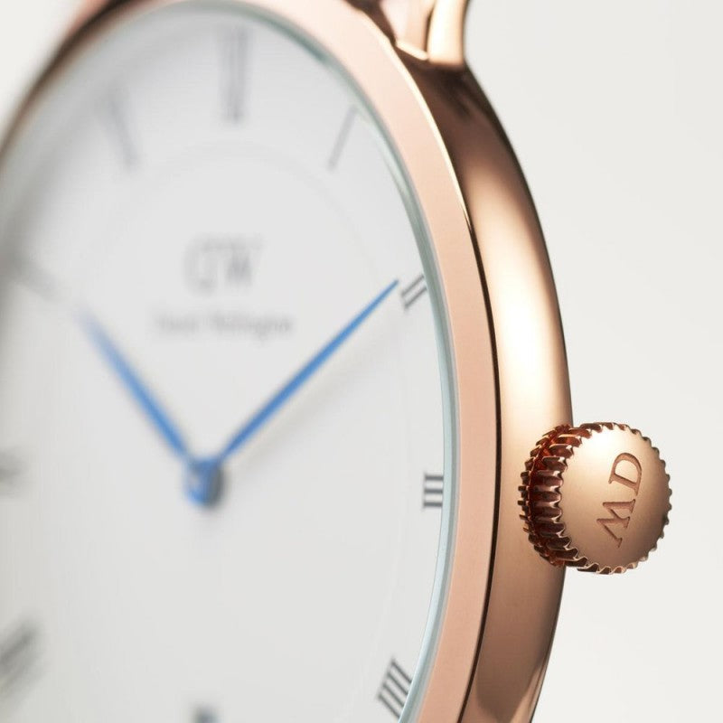 Close-up detail of Dapper watch dial showing white face, blue hands, Roman numerals, and rose gold crown