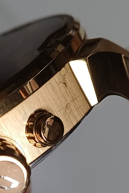 Gold chronograph watch side view highlighting crown and pusher button design