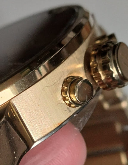 Close-up side profile of gold watch case showing brushed finishing and chronograph pushers