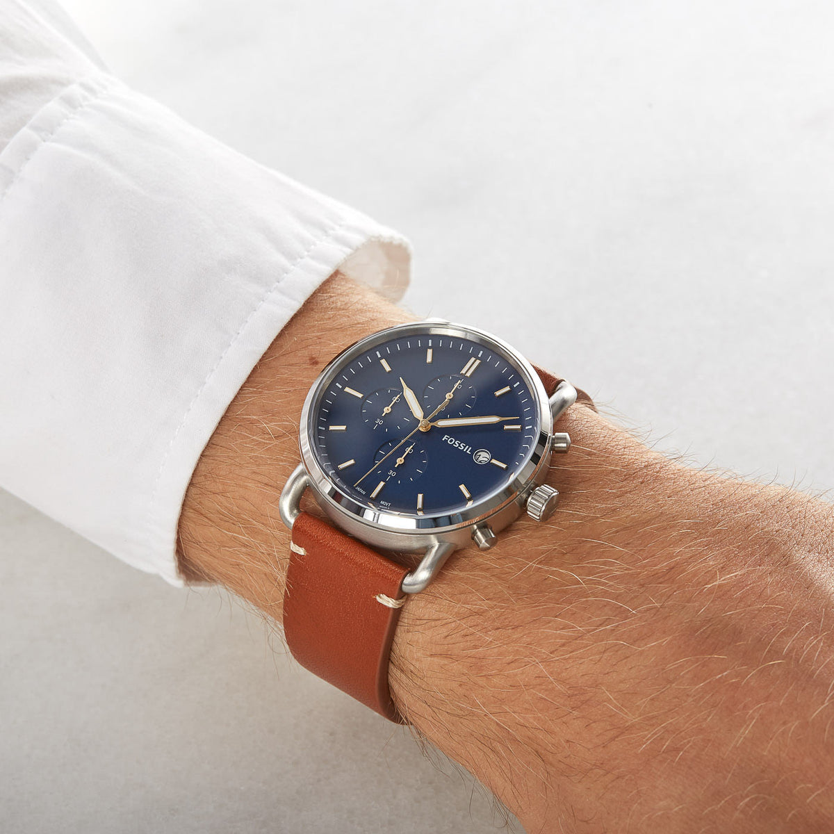 Fossil Commuter chronograph watch worn on wrist with blue dial and cognac brown leather strap