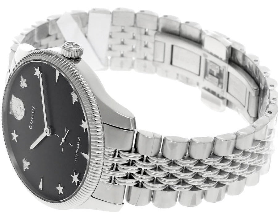 Gucci G-Timeless automatic watch on wrist showing stainless steel bracelet and black dial