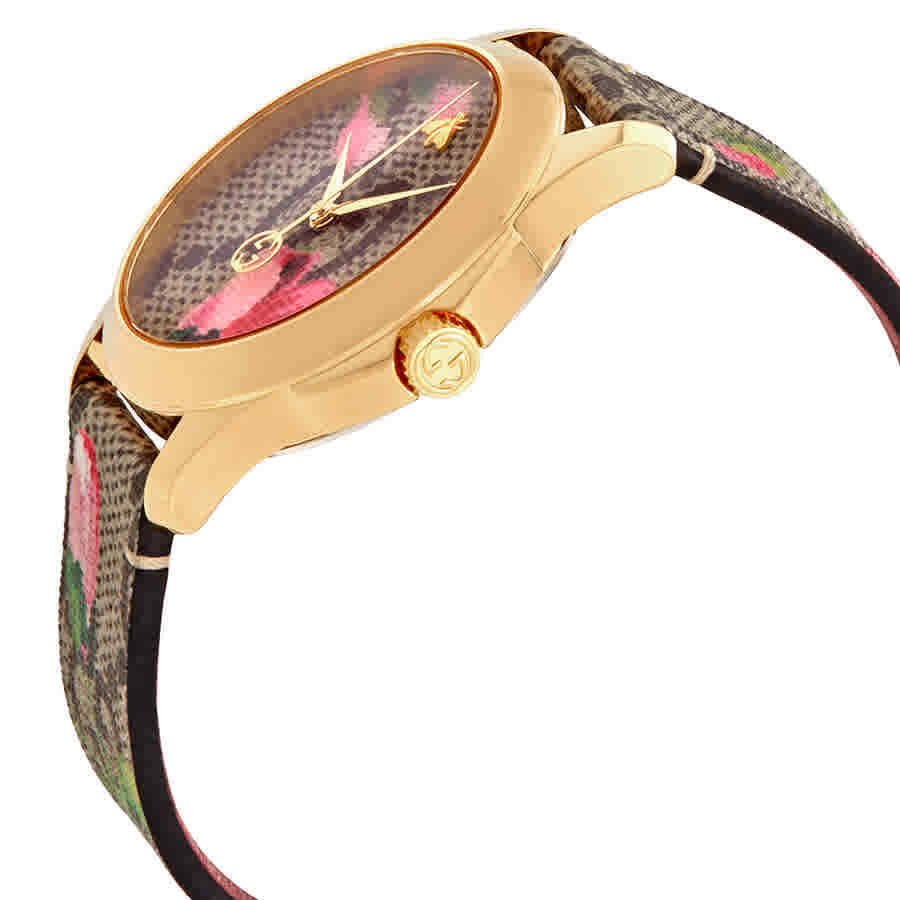 Gucci G-Timeless watch worn on wrist showing gold case and pink floral canvas strap
