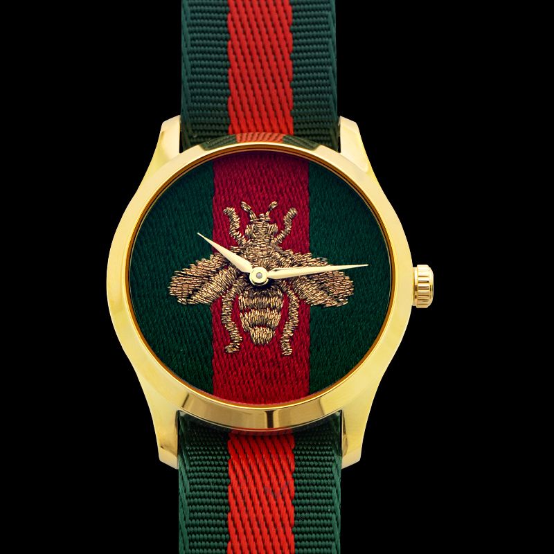 G-Timeless 38mm watch front view with embroidered bee, gold case, and green-red nylon strap