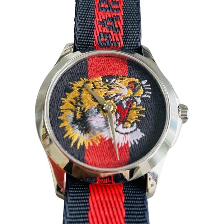 Gucci G Timeless watch three-quarter view with tiger embroidered dial and navy striped strap