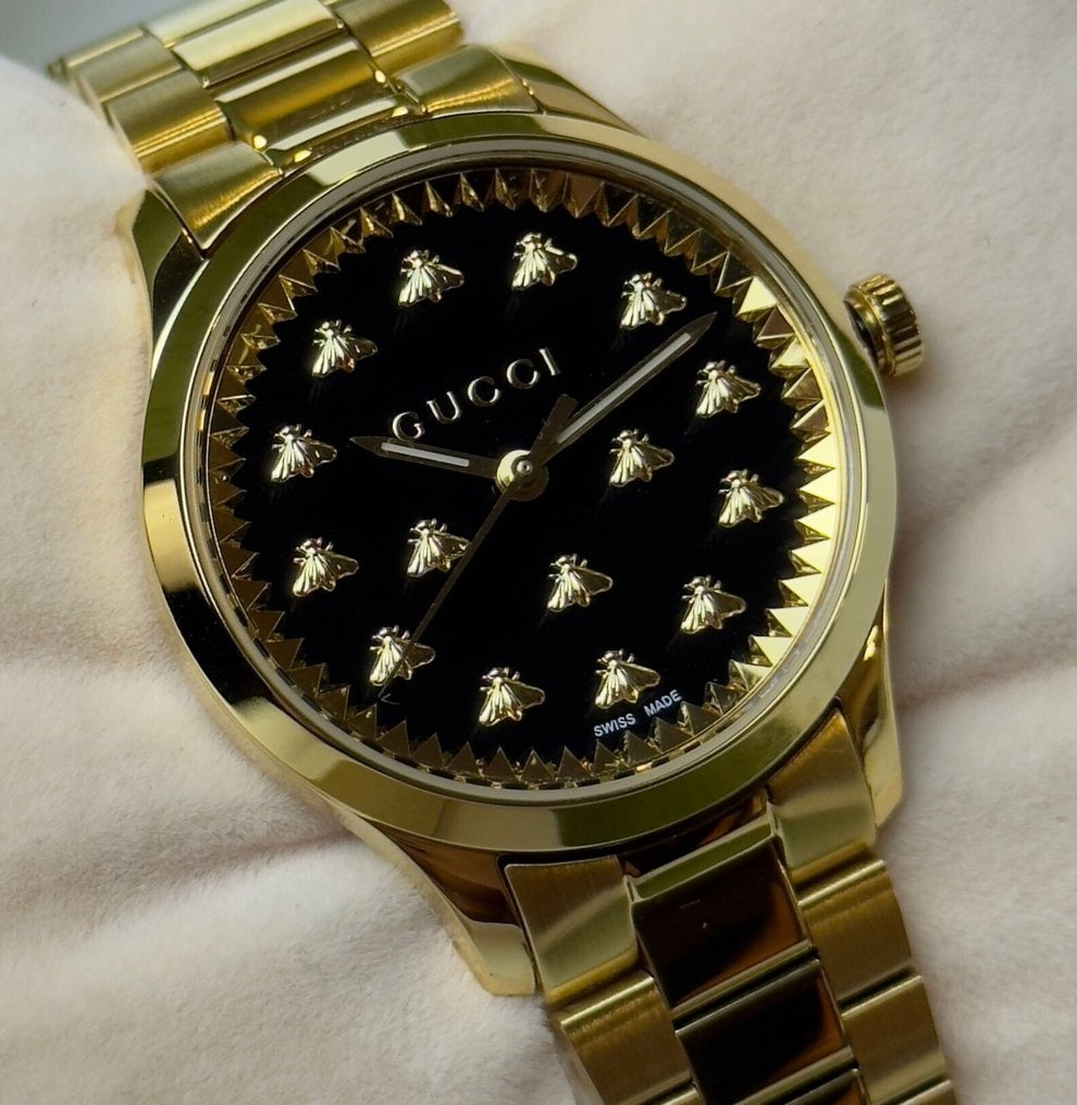 Close-up of Gucci G Timeless black dial with gold bee indices and Gucci branding