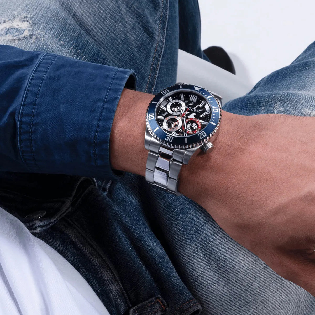 GUESS Axle silver watch on wrist showing skeleton dial and blue bezel