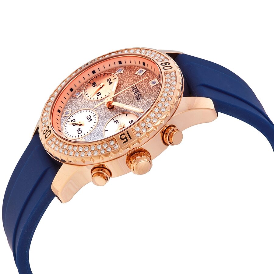 Angled side view of Guess Confetti watch showing rose gold case, glitter dial, and navy rubber strap