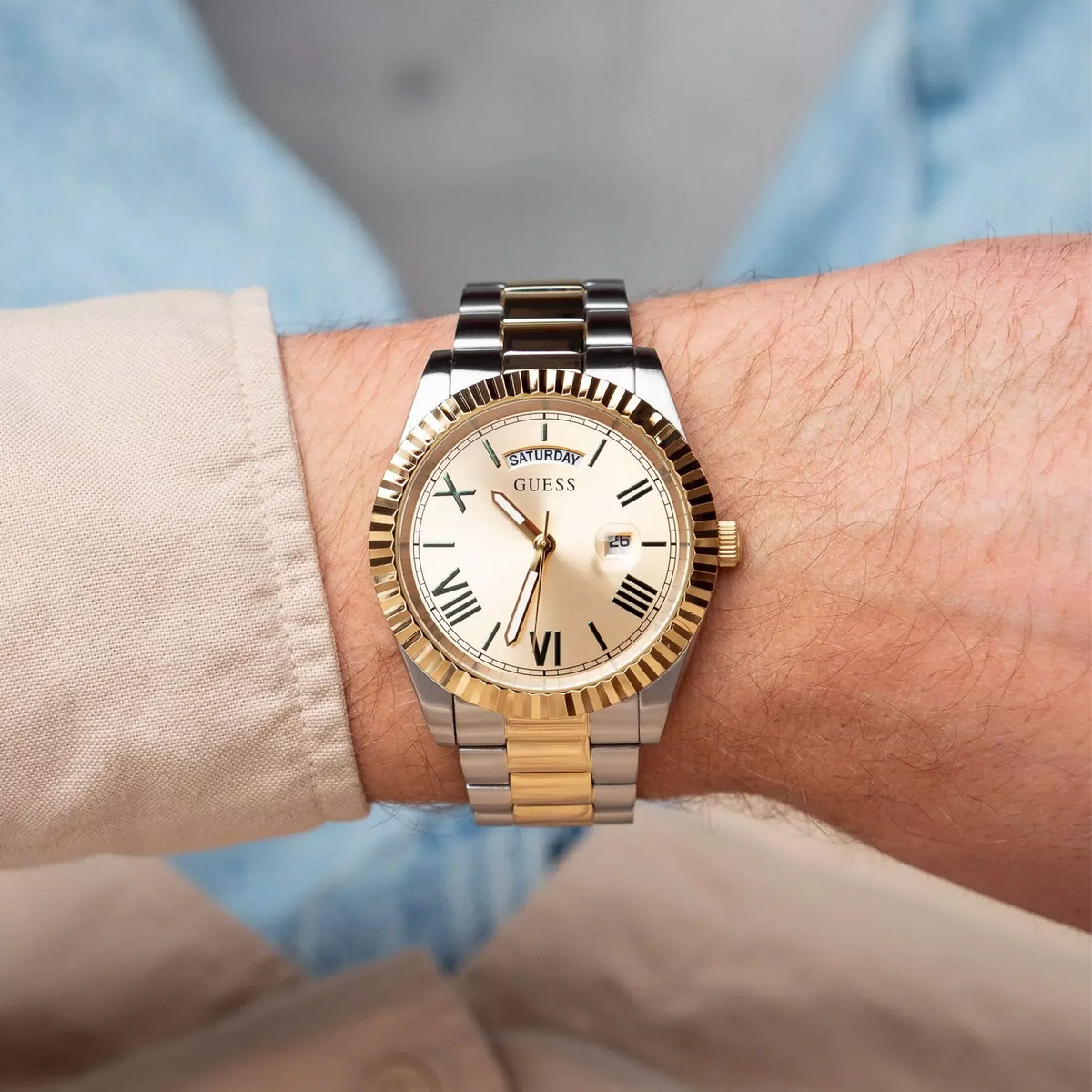 GUESS Connoisseur watch worn on wrist with light blue and beige clothing