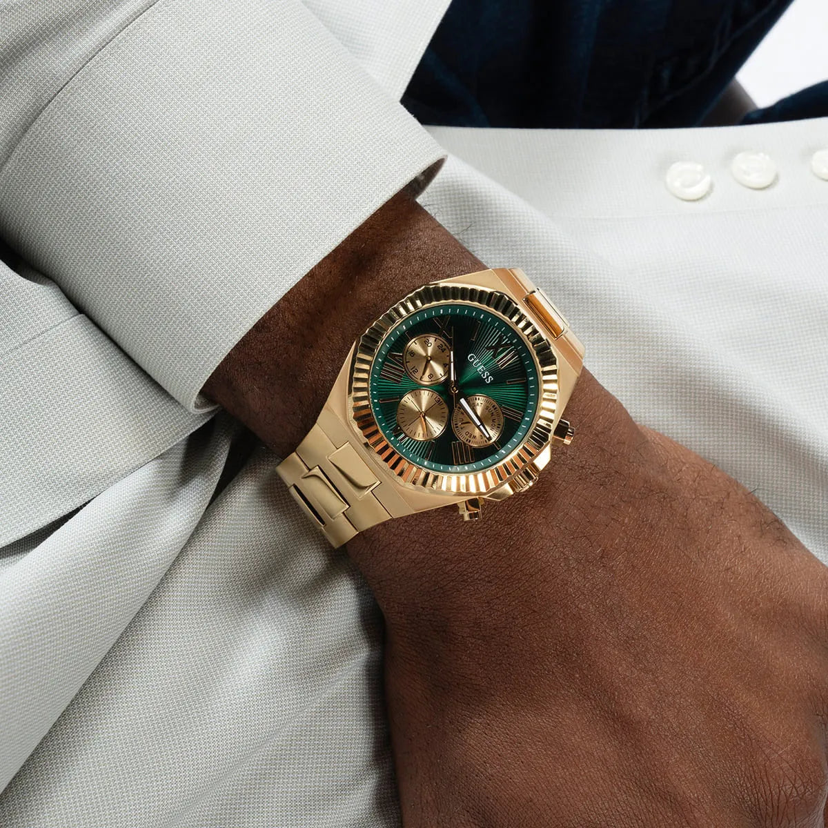 GUESS Equity chronograph watch worn on wrist with gold tone case and green dial