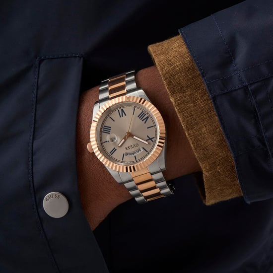 GUESS GW0265G13 two-tone mens watch worn on wrist with navy jacket and brown leather accessory