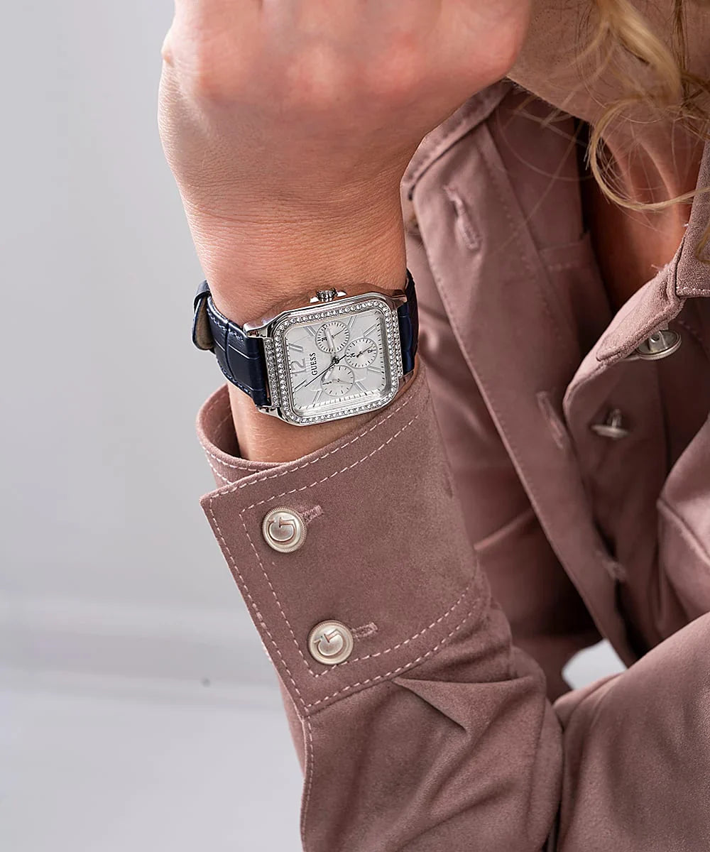 GUESS blue leather women's chronograph watch worn on wrist with pink sleeves