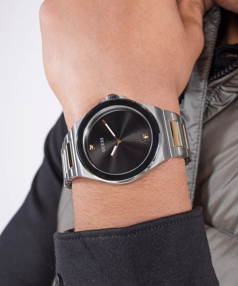 GUESS black dial watch worn on wrist with two-tone stainless steel bracelet