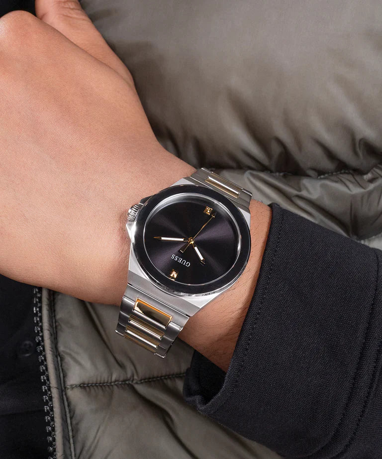 GUESS analog watch on wrist showing black dial and gold-tone hands, side-on view